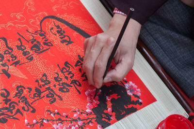 High angle view of person holding paper with text on table