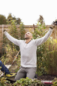 Mature man with arms outstretched in garden