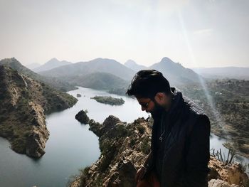 Young man looking at mountains against sky