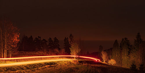 Road amidst trees against sky during sunset