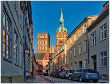 Cars on street amidst buildings against clear blue sky