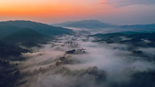 Aerial view of mountains against dramatic sky during sunset