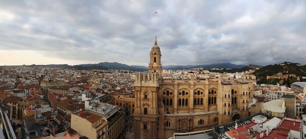 High angle view of buildings in city against cloudy sky