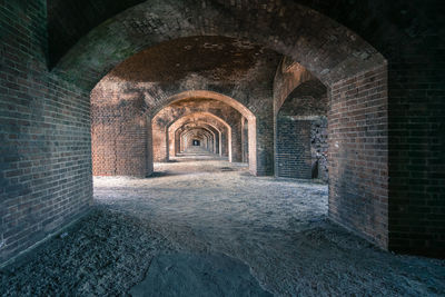 Empty corridor of mysterious brick building  with light coming through arches,