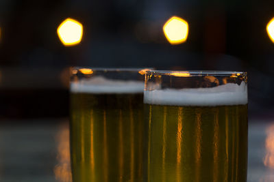 Glasses of beer with blurred lights on background