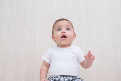 Portrait of cute boy standing against wall