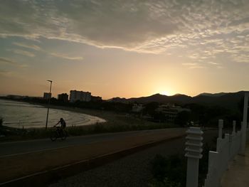 Road by city against sky during sunset