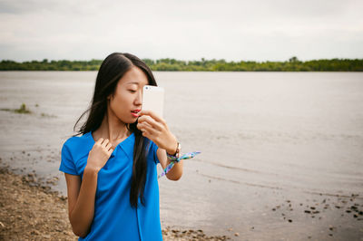 Young woman taking selfie while standing at riverbank