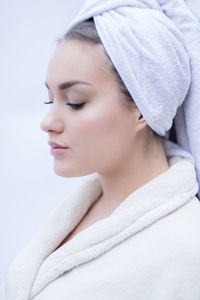 Close-up of teenage girl wearing bathrobe against white background