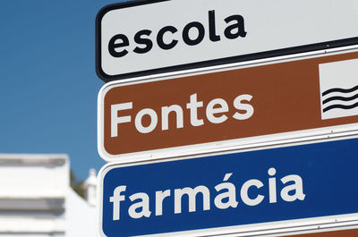 Low angle view of road sign against clear blue sky