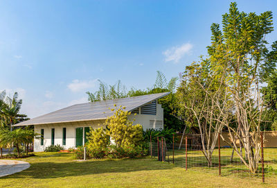 Trees and house on field against sky