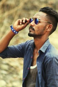 Portrait of young man holding sunglasses