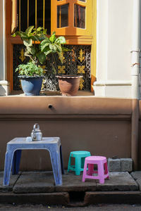 View of plastic table and chairs in front of potted plants on window sill of house