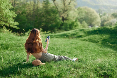 Rear view of woman sitting on grassy field