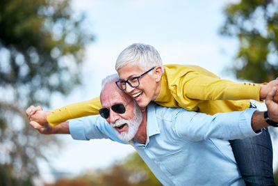 Happy senior man giving piggyback ride to woman in park