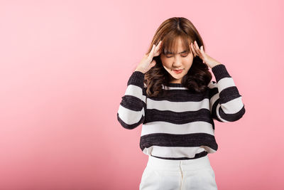 Young woman standing against yellow background