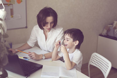 Tutor deals with the preschooler with a laptop, a real home interior, the concept of childhood 
