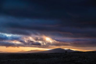 Scenic view of silhouette landscape against dramatic sky during sunset