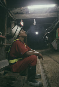 Side view of worker smoking cigarette while sitting underground tunnel