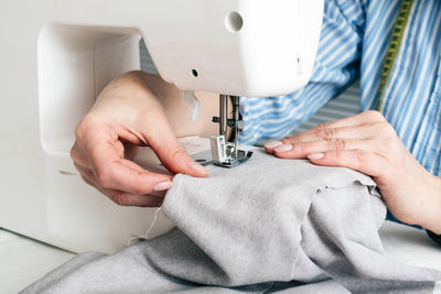 Midsection of craftswoman sewing textile on machine at workshop