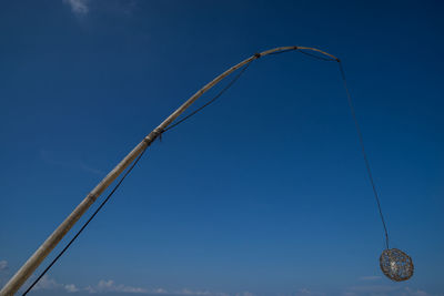 Low angle view of lighting equipment hanging against blue sky