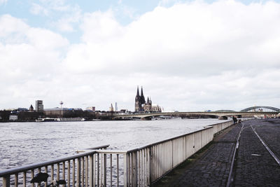 Bridge over river by buildings in city against sky