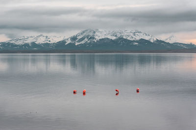 Scenic view of lake by snowcapped mountains against sky