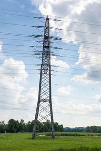 Low angle view of electricity pylon on field against sky