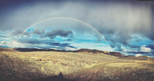 Scenic view of rainbow over land against sky
