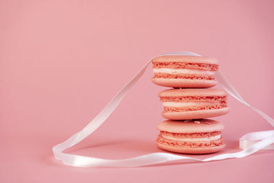 Delicious pink macaroon cookies with white ribbon on a pink background. a great idea for a gift.