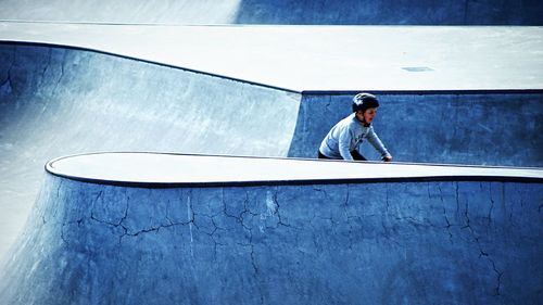 Full length of man standing against wall against blue sky