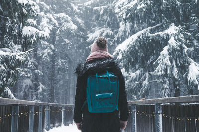 Rear view of woman standing on footbridge during winter