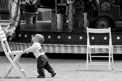 Cute baby boy walking by carousel at amusement park