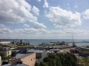 View of town by sea against cloudy sky