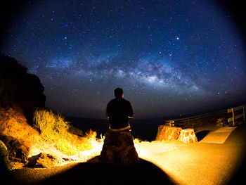 Rear view of man standing on field against milky way