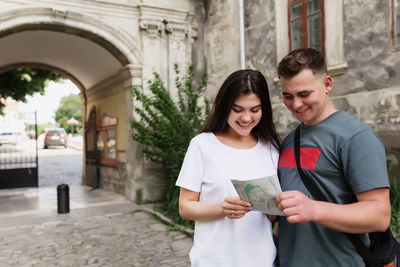 Young man and woman standing against building