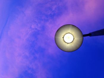 Low angle view of illuminated light bulb against blue sky