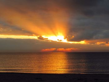 Scenic view of sea against dramatic sky during sunset