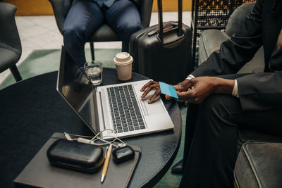 Young businesswoman holding credit card while using laptop at hotel lounge