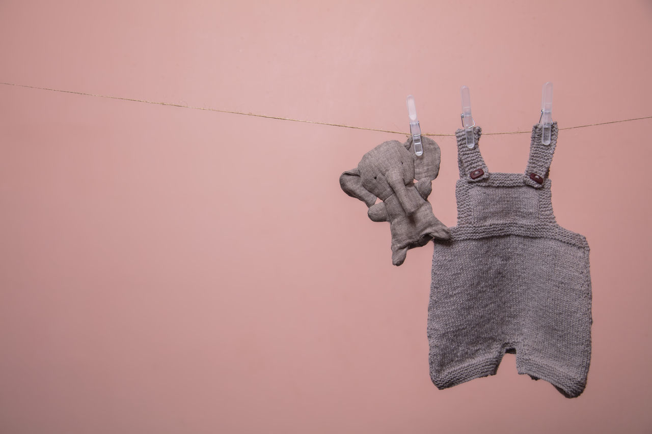 LOW ANGLE VIEW OF CLOTHESPINS HANGING AGAINST WALL