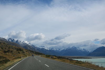 Road leading towards mountains against sky