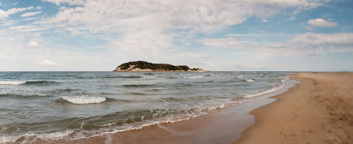 Surf on beach against cloudy sky