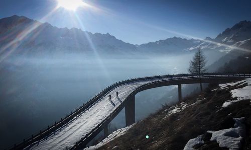 Bridge over river against mountains during winter