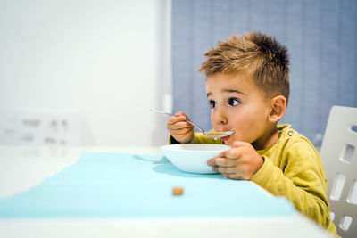 Portrait of boy sitting on table at home