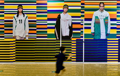 Full length of a young man standing against multi colored wall