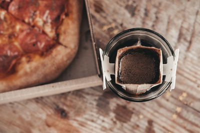 Brewing coffee in a drip bag in a transparent glass, on a wooden background. hot ground drip coffee