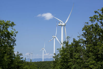 Low angle view of wind turbines on landscape against sky