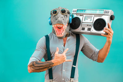 Man in mask holding boom box against blue background