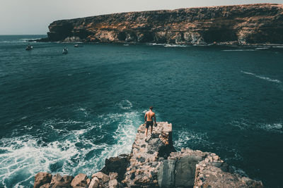 High angle view of man walking on rock formation against sea