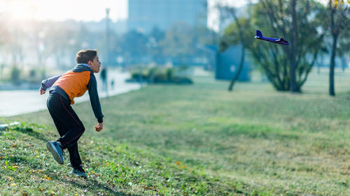 Boy playing with airplane glider toy in the park.